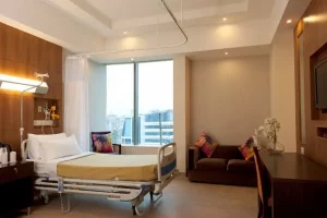 Private patient room with hospital bed and seating area at HSCT Hospital India